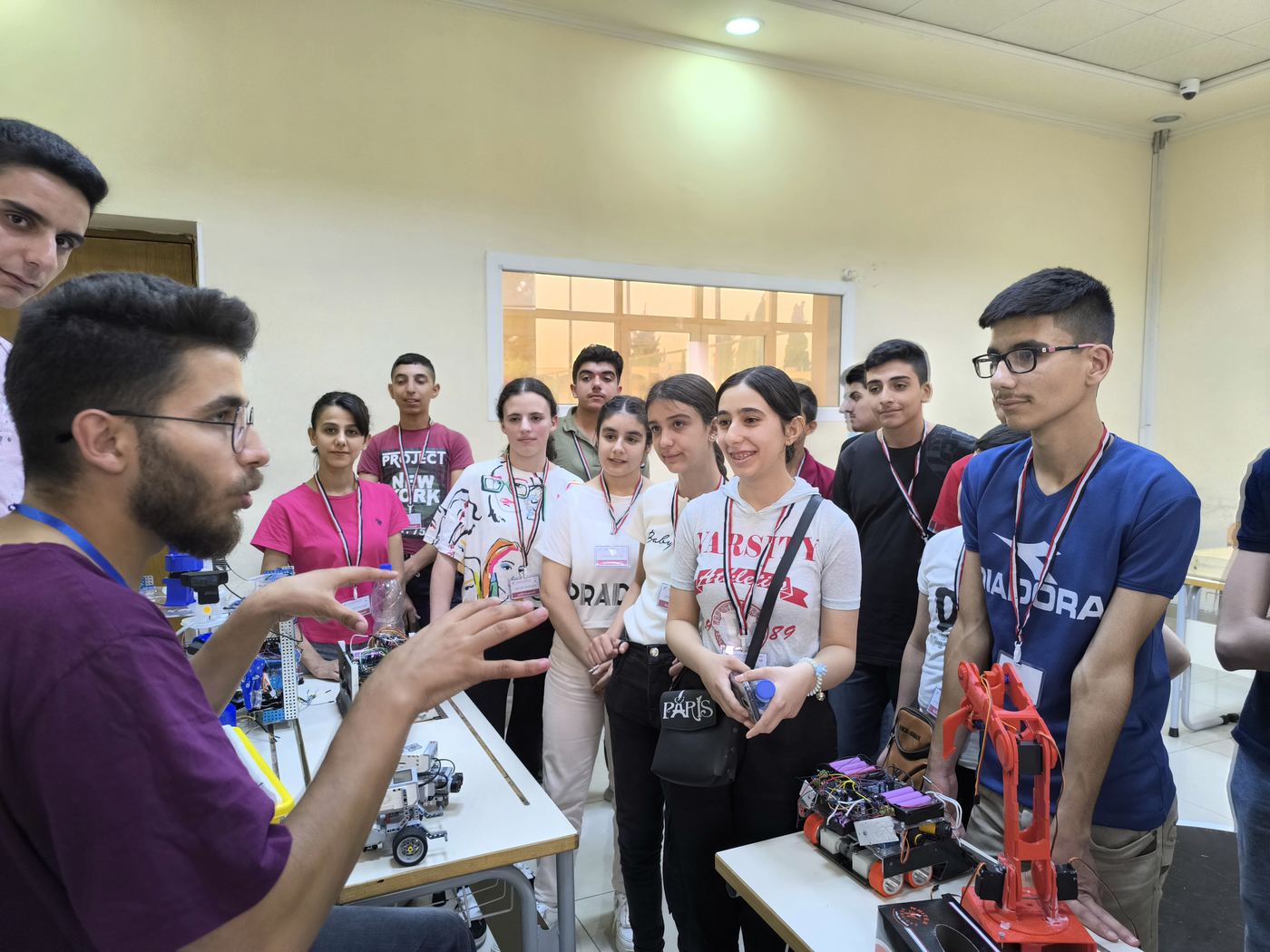 Teens gathered around a robot arm during a workshop